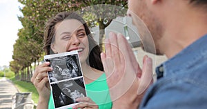 Happy couple waiting for the birth of a baby. A woman shows a picture of an ultrasound to her husband. Emotion of joy