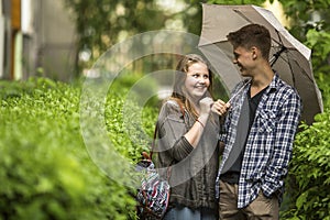 Happy couple on a walk in the park with umbrella.