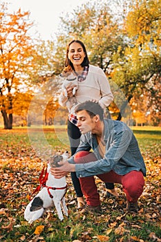 Happy couple walking in autumn park and playing with dogs