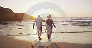 Happy couple, walking on beach and hand holding in sunset and playful on holiday, outdoor and back. Retirement, elderly