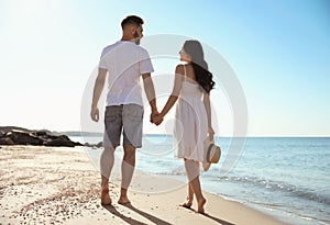 Happy couple walking on beach near sea. Honeymoon trip