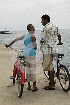 Happy Couple Walking With Bicycles On Beach