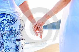 Happy couple walking hand in hand on white sand beach Relaxing at sunset during vacation