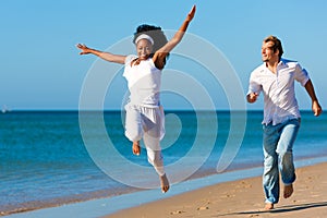 Happy couple walking and running on beach