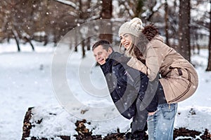 Happy couple walking in snowy winter forest, spending Christmas