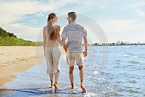 happy couple walking in water along summer beach