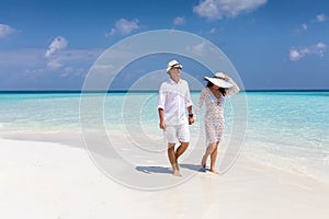 Happy couple walks down a tropical beach