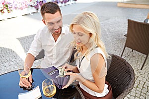 Happy couple with wallet paying bill at restaurant