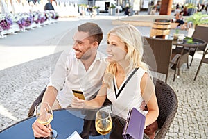 Happy couple with wallet paying bill at restaurant