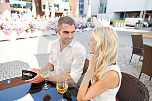 Happy couple with wallet paying bill at restaurant