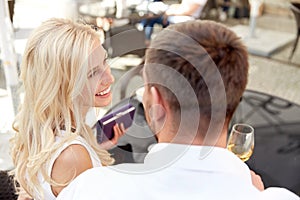 Happy couple with wallet paying bill at restaurant