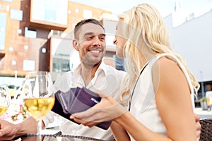 Happy couple with wallet paying bill at restaurant