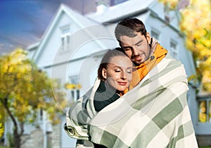 happy couple in warm blanket over house in autumn