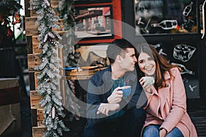 Happy couple in warm clothes drinking coffee on a Christmas market