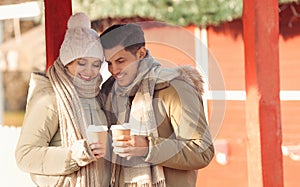 Happy couple in warm clothes with drinks at winter fair