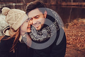 Happy couple in warm hat and scarf walking outdoor in autumn forest, cozy mood