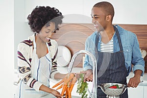 Happy couple washing vegetables