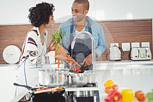 Happy couple washing vegetables