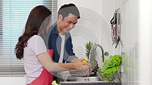 Happy couple washing vegetables in the sink in the kitchen at home. cooking together