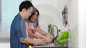 Happy couple washing vegetables in the sink in the kitchen at home. cooking together