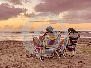 Happy couple watching enjoy luxury sunset on the beach during summer vacations. beautiful sky day