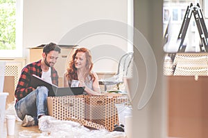 Happy couple watching photobook and packing stuff while moving-out