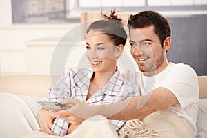 Happy couple watching television in bed