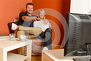 Happy couple watching tv evening changing channels