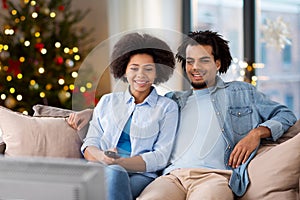 Happy couple watching tv at home on christmas