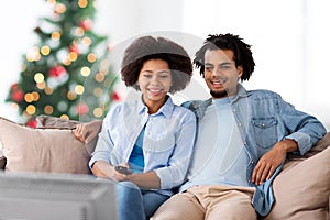 Happy couple watching tv at home on christmas