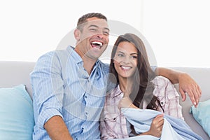 Happy couple watching TV on sofa