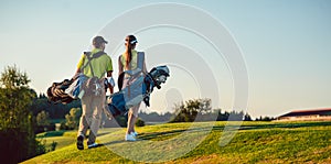 Happy couple wearing golf outfits while carrying stand bags