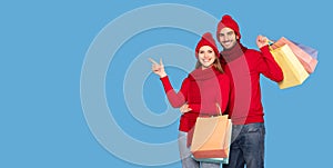 Happy Couple Wearing Winter Hats Holding Shopping Bags Pointing At Copy Space