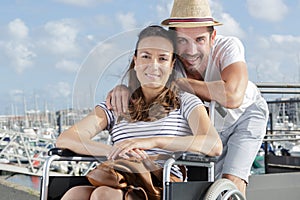 Happy couple in wheelchair posing in port