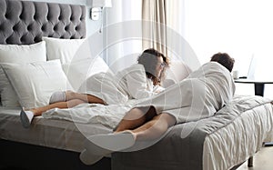 Happy couple in white bathrobe on a bed in a hotel.