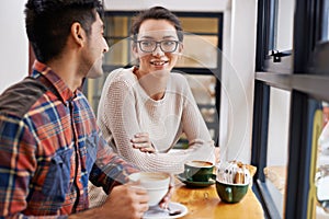 Happy couple, window and relax with coffee at cafe for chatting, talking or social bonding. Young man and woman with