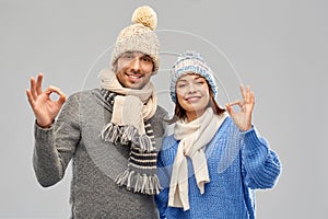 Happy couple in winter clothes showing ok sign