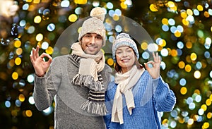 happy couple in winter clothes showing ok sign