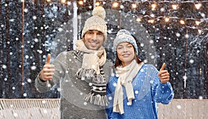 happy couple in winter clothes showing thumbs up