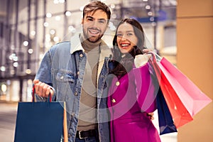 Happy couple in winter jackets enjoys shopping carrying bags outside