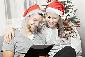 Happy couple write list for christmas on sofa
