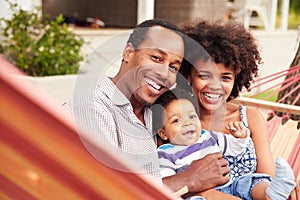 Happy coupleï¿½with young child sitting in a hammock