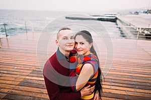 Happy couple of young lovers posing and smiling on berth in the rainy day. Romantic honeymoon