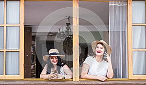 Happy couple of young woman caucasian friends have fun together at the bar window enjoying the phone internet connection -