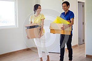 Happy couples hold paper boxes that hold personal belongings and move items to their new home