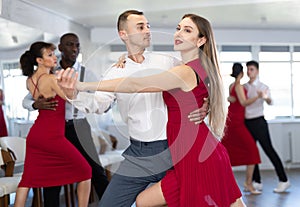 Happy couples young male and female dancing samba in dance room during celebration or party