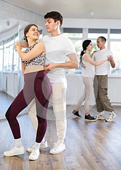 Happy couples young male and female dancing samba in dance room during training