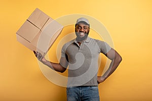 Happy courier with a box to deliver. emotional expression. Yellow background