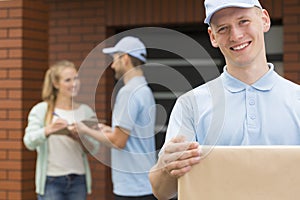 Happy courier holding a package for woman