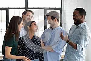 Happy coworkers congratulating excited Indian female employee